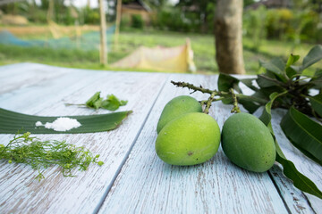 Some raw mango or kaccha aam with some ingrediants like chilli, salt, pudina and garden presly