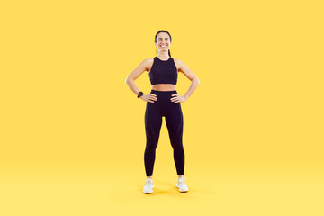 Fototapeta na wymiar Full length portrait of sportive fit smiling young woman in sportswear isolated on yellow studio background do sports. Toned happy female trainer or coach exercise workout for good body shape.