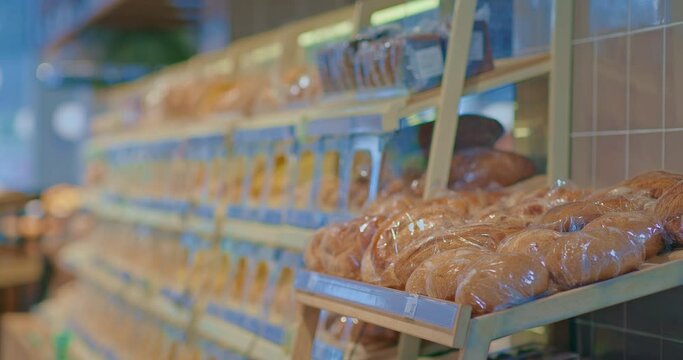 Baguettes and loaves of bread lie in a row on the supermarket windows. Beautifully laid out goods on the shelves of a grocery store. Modern closed showcases of the bread department. 4k, ProRes