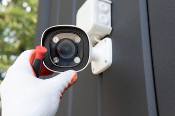 Close-up of surveillance camera installation, male hand holds cctv camera.