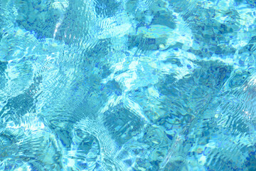 Blurred transparent blue water in swimming pool with waves in sunlight. Trendy abstract surface texture or nature background.