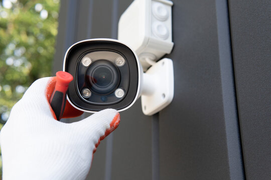 Close-up Of Surveillance Camera Installation, Male Hand Holds Cctv Camera.