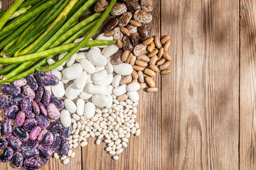 Different varieties of beans on a wooden table. Harvest and vegetarianism concept.