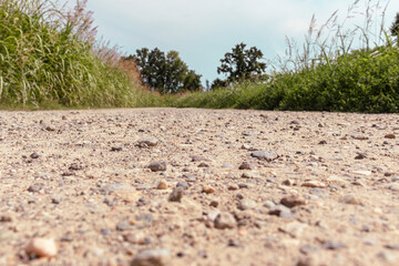 Low angle view on an gravel road leading to an unknonwn point in the forest. Diminishing perspective. Selective focus. Copy space.