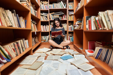 Young brunette woman in a library full of books