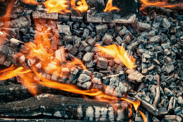 Bright orange flashes of fire from a bonfire on coals