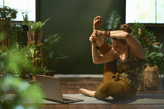 smiling stylish woman in green living room doing yoga