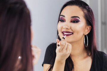 Woman Applying Lips Gloss In Front Of Mirror