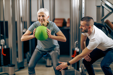 Fototapeta na wymiar Senior Woman Doing Workout With Coach In The Gym