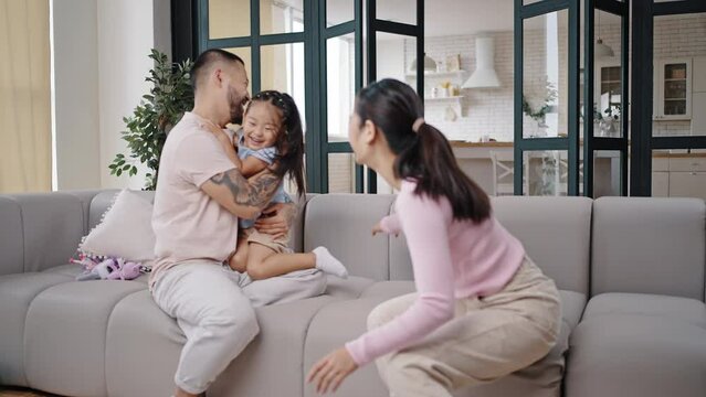 Asian daughter enjoys playing with parents in living room