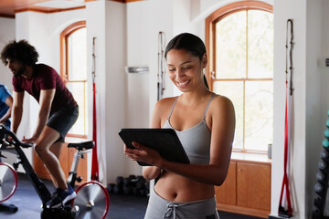 Fototapeta na wymiar Confident biracial young woman using digital tablet at the gym