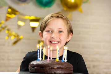 happy birthday child sitting in front of chocolate cake with candles.