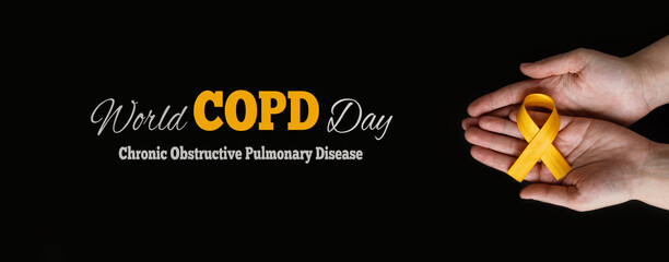 World COPD day. Medical campaign against Chronic Obstructive Pulmonary Disease in november. Woman's hands hold an orange ribbon on a black background