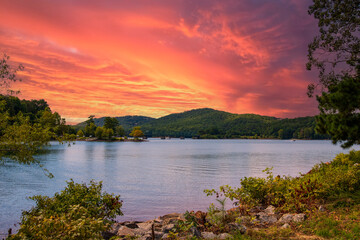 a gorgeous summer landscape at Lake Allatoona with green water surrounded by lush green trees, grass and plants with powerful clouds at sunset at Red Top Mountain State Park in Acworth Georgia USA