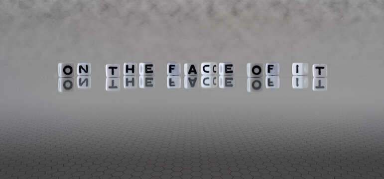 on the face of it word or concept represented by black and white letter cubes on a grey horizon background stretching to infinity