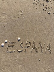 on the beach is carved with letters in the smooth sand the writing Espana