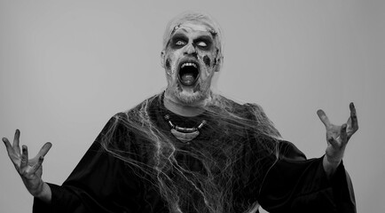Sinister man in carnival costume of Halloween crazy zombie with bloody wounded scars face...