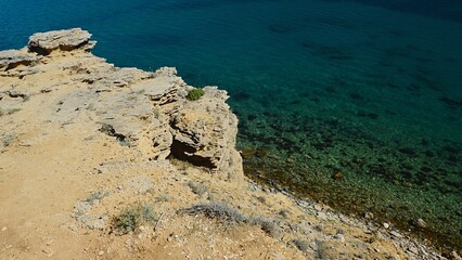 Shoreline arid rock above Sveta Maria beach on Pag Island, Croatia, clear azure blue water visible under the steep slope. 