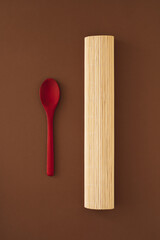 Red spoon and bamboo asura on brown background. Minimal concept for cook or eat. Colorful minimalism. Flat lay.