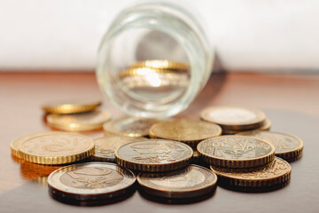 Euro coins pouring form a jar into a wooden table. Concept of finance, savings, EU currency, business