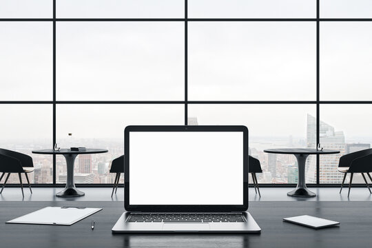 Close up of empty white laptop screen on gray office desktop with supplies on panoramic window and city view background. Mock up, 3D Rendering.