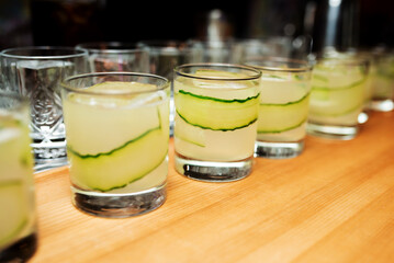 Cocktail in wine glass with alcohol, cucumber slices and ice cubes on the table at restaurant side view