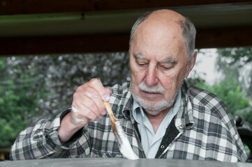 aged senior man painting a garden table