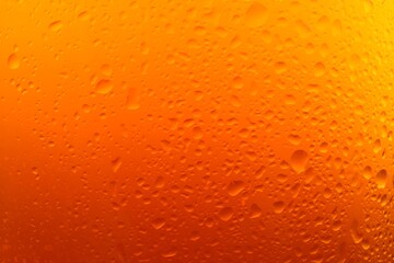 Glass of tasty cold beer with condensation drops as background, closeup