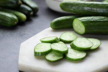 Whole and cut fresh ripe cucumbers on white board, closeup