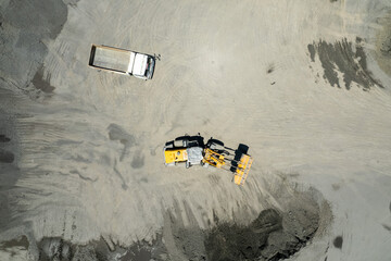 Sand loaders are shoveling rocks into dump trucks. © waranyu
