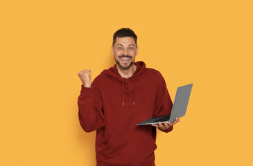 Happy man with laptop on orange background