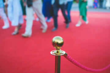 Red carpet with ropes and golden barriers on a luxury party entrance, cinema premiere film festival event gala ceremony, wealthy rich guests arriving, outdoor decoration elements, summer sunny day