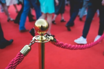 Red carpet with ropes and golden barriers on a luxury party entrance, cinema premiere film festival event gala ceremony, wealthy rich guests arriving, outdoor decoration elements, summer sunny day