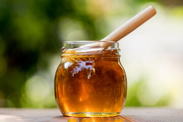 Honey in a glass bottle on nature background.