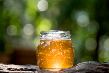 Honey in a glass bottle on nature background.