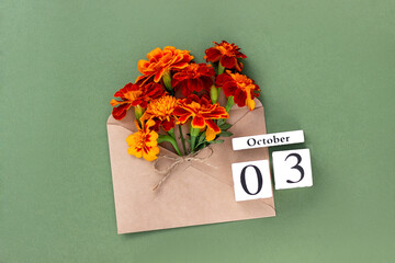 October 3. Bouquet of orange flower in craft envelope and calendar date on green background. Minimal concept Hello fall. Template for your design, greeting card