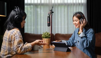 Shot of two smiling radio hosts are talking while recording podcast in broadcasting studio together.