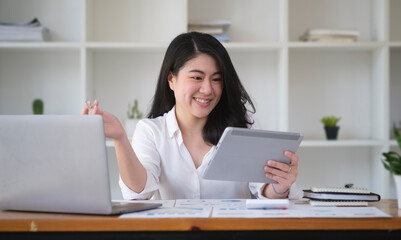 Attractive young businesswoman sitting in modern office and using digital tablet.