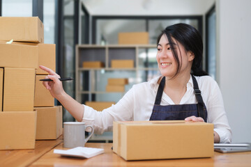 Young woman startup small business entrepreneur preparing parcel boxes of product for deliver to customer..