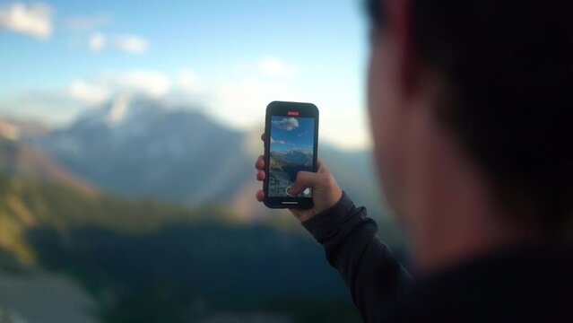 Close up of causian hand holding phone, filming epic mountain views