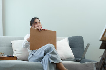 young Asian woman, art work on the sofa in her spare time.