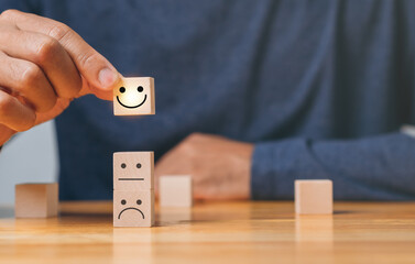 Top Smile Satisfaction. Best excellent business services rating customer experience. Satisfaction survey concept. Hand of a businessman chooses a smiley face on wood block cube.