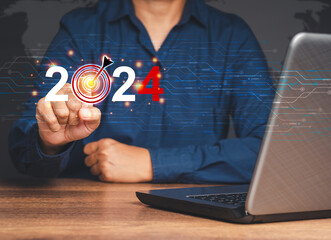 Close-up of hand pointing to a goal at a digital 2024 calendar on virtual screen while sitting at the table