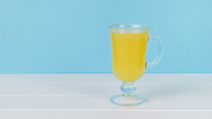 A glass glass on a leg on a white wooden table on a blue background.