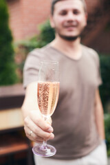 A friend raises a glass of champagne in your honor at a house party. Selective focus. Vertical photo.