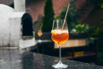 A glass with a Venetian Spritz cocktail on the table near the pizza oven. Relaxing in the backyard of the house. Front view.