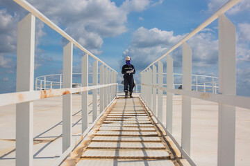 Male walking the up stairway inspection visual record stairs on the tank roof white