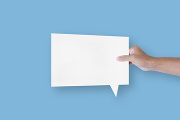 Fototapeta premium Hand holding a square shaped white paper bubble speech bubble isolated on light blue background. communication bubbles