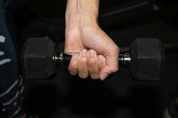 Mains soulevant une altère en fonte et en inox ligament en tension