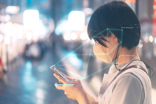 Identity scan young adult asian woman wear face and mask via smartphone at outdoor on night